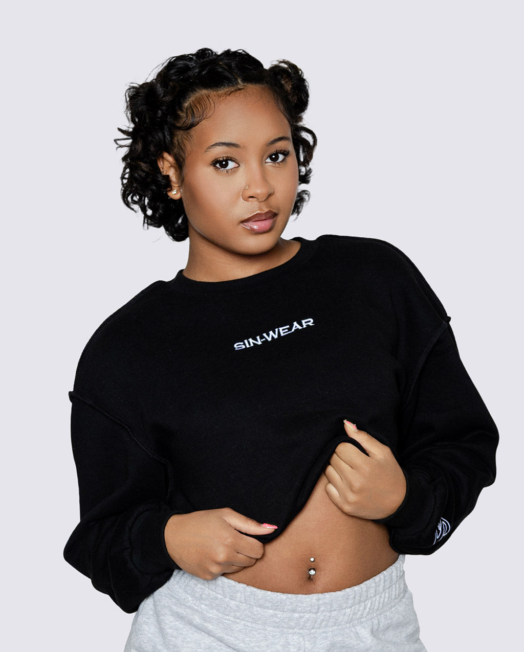 Person wearing a black sweatshirt with 'sin-wear' branding on a light gray background