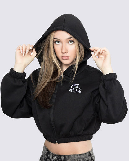 Woman wearing a black crop zip hoodie with 'Sin-Wear" logo on a light gray background