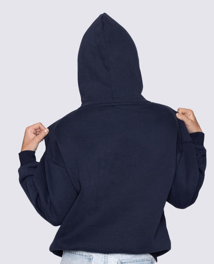 Person wearing a navy blue hoodie with the hood up on a light gray background