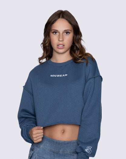 Woman wearing a blue cropped sweatshirt with 'SIN-WEAR' branding on a light gray background