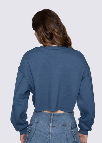 Person wearing a blue cropped sweatshirt and jeans on a white background