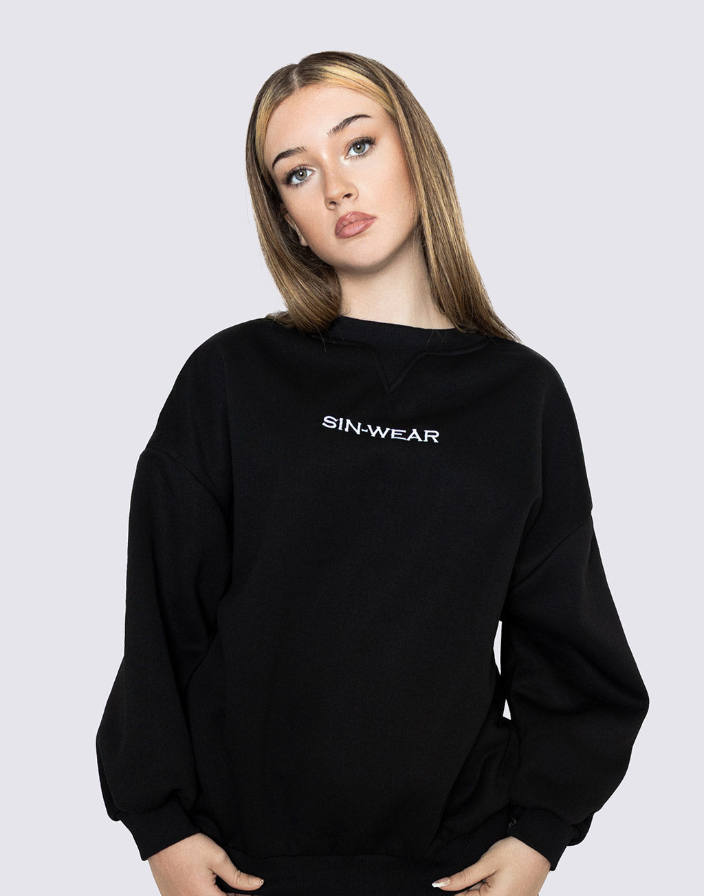 Person wearing a black sweatshirt with 'SIN-WEAR' logo on a light gray background