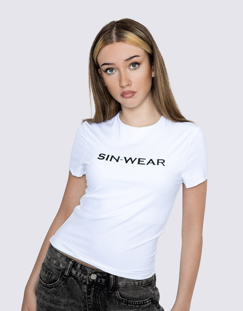 Woman wearing a white dry-fit t-shirt with 'SIN WEAR' text on a plain background