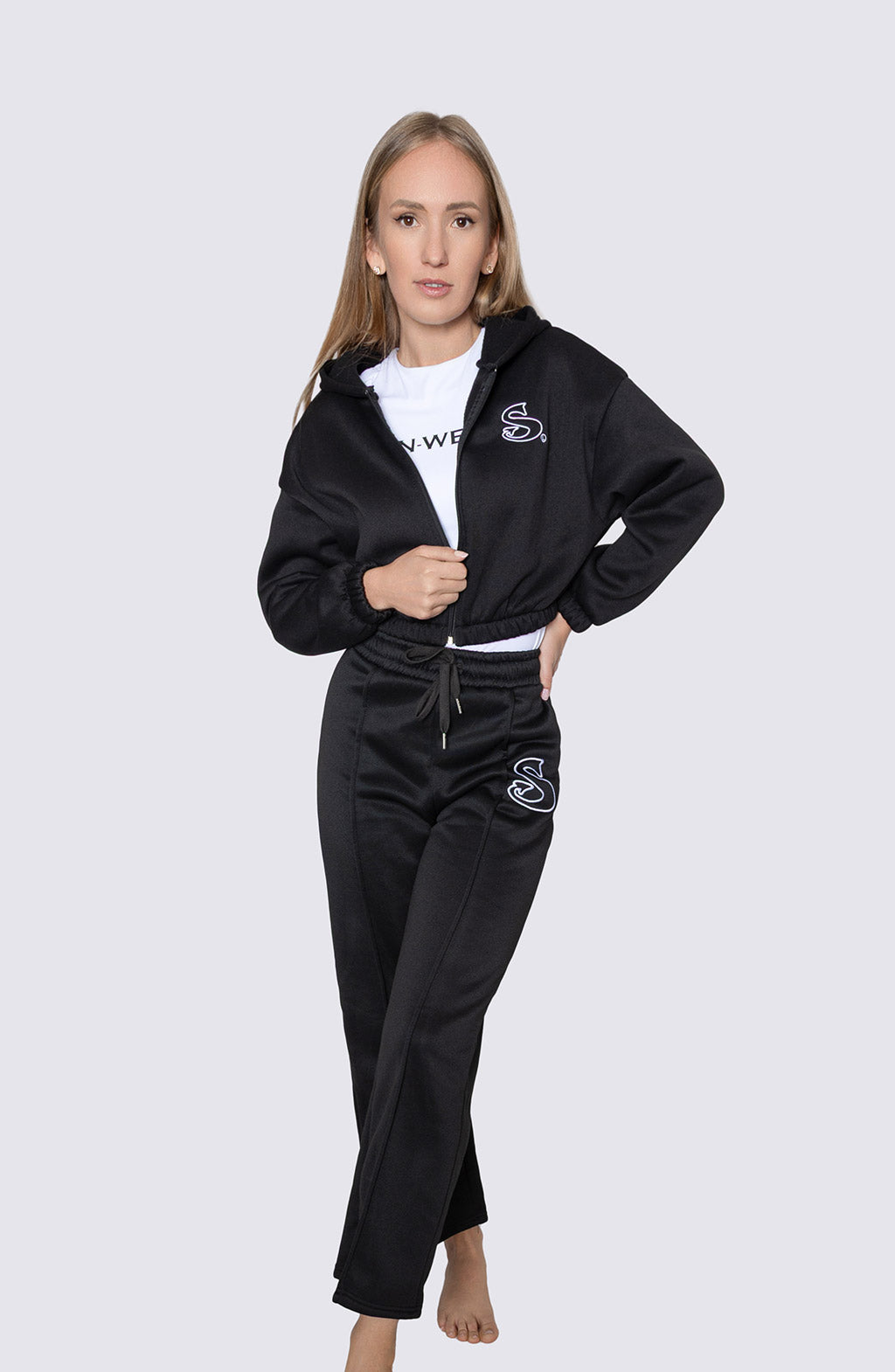 Woman wearing a black tracksuit with a 'Sin-Wear' brand logo on a white background