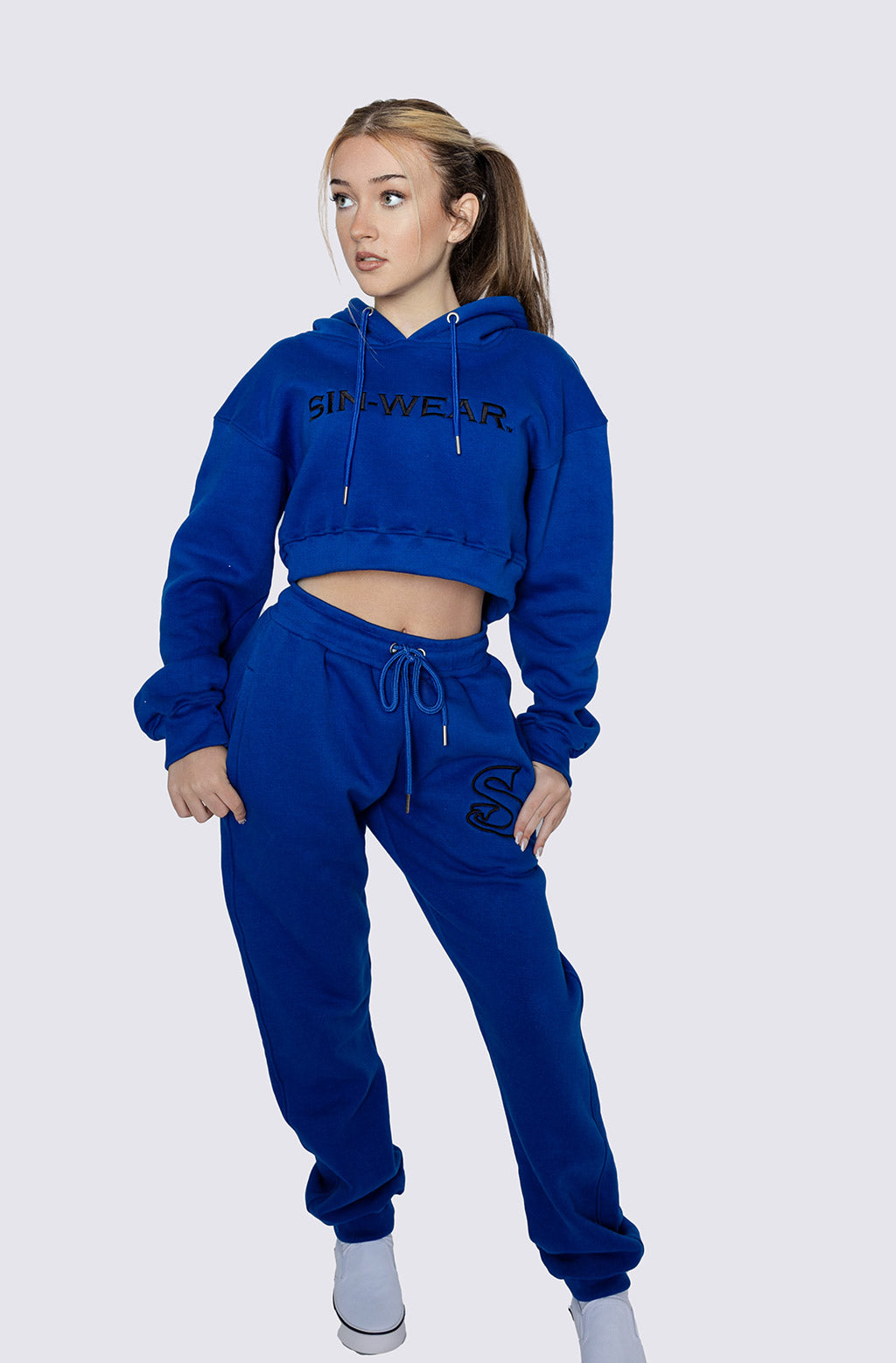 Person wearing a blue tracksuit with visible Sin-Wear branding on a white background