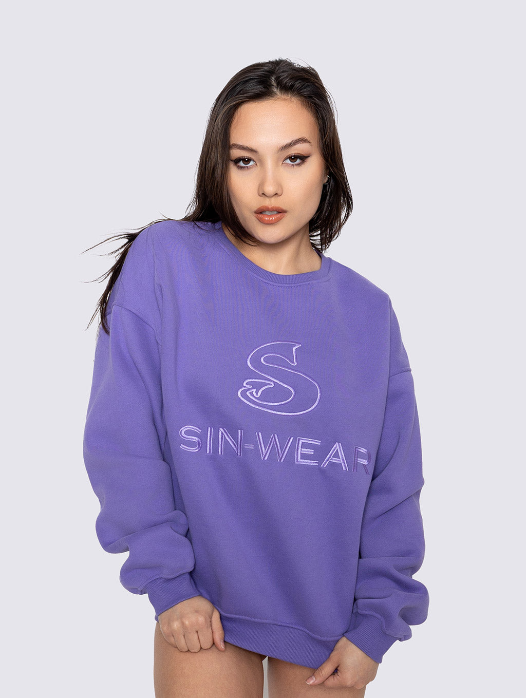 Person wearing a purple sweatshirt with 'SIN-WEAR' logo on a white background