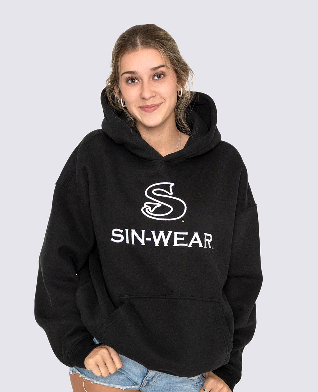 Person wearing a black hoodie with 'SIN-WEAR' logo on a light gray background
