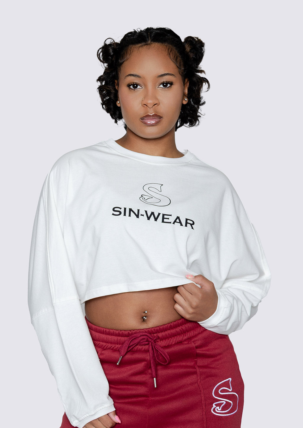 Person wearing a white 'SIN-WEAR' long sleeve cotton top and red pants on a white background