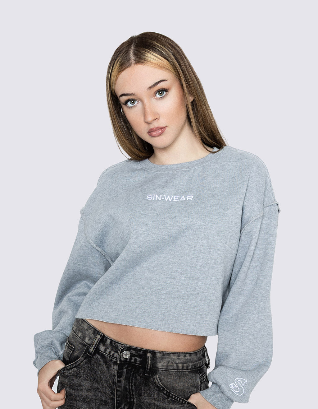 Woman wearing a gray cropped sweatshirt with 'Sin-Wear' branding on a light gray background