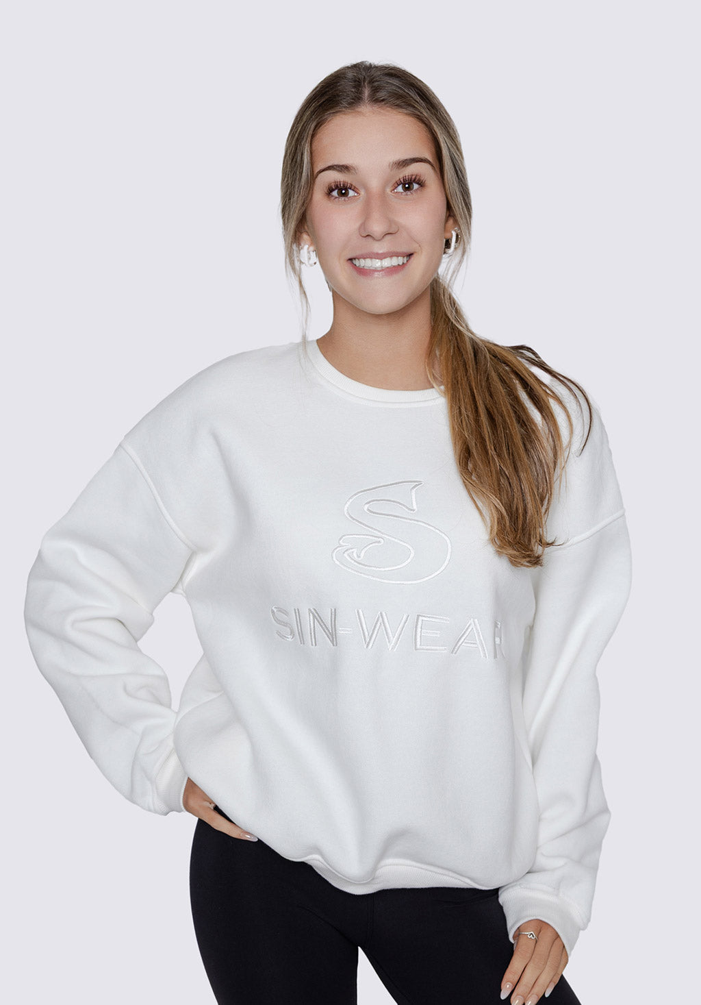 A women wearing a white sweatshirt with 'Sin-Wear' branding on a plain background