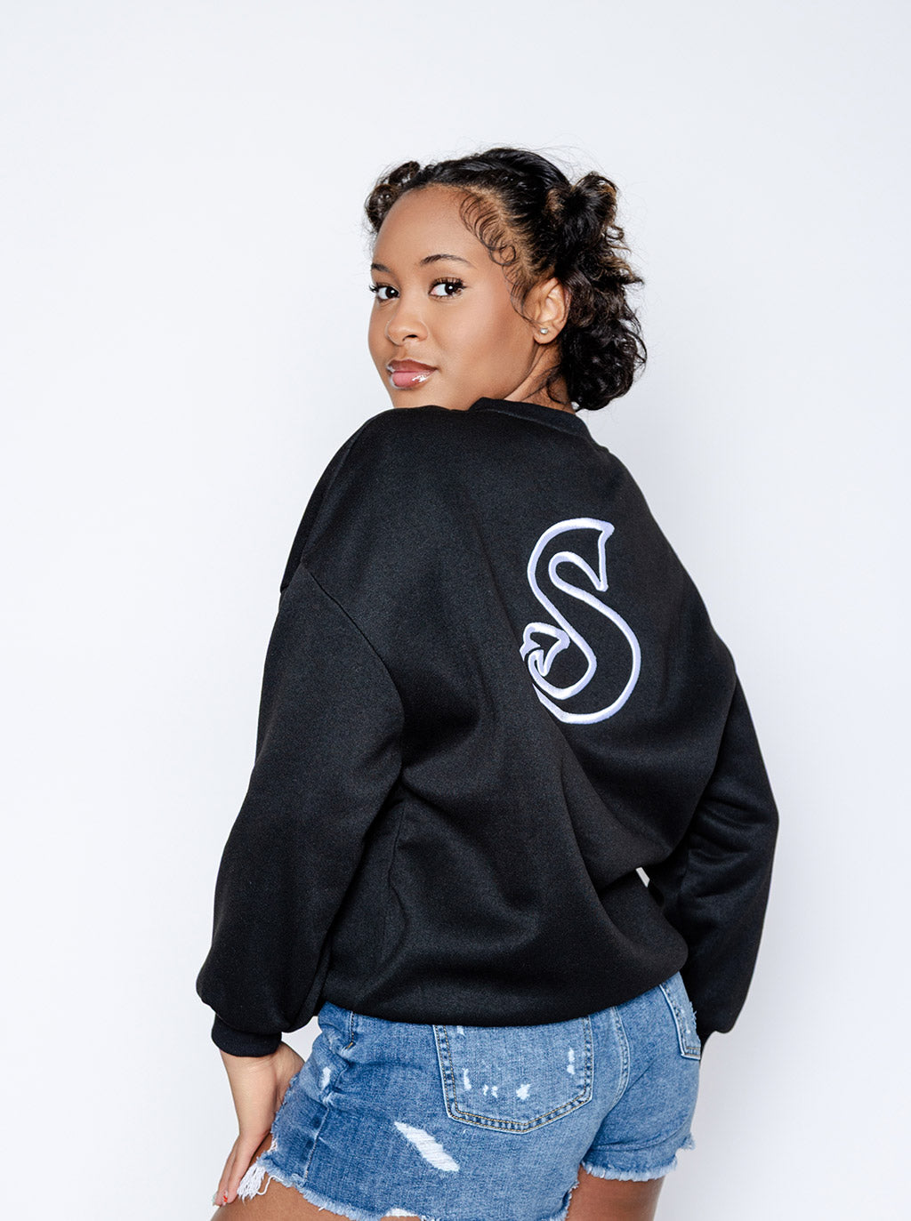 Person wearing a black sweatshirt with a white 'Sin-Wear' logo on the back, standing against a plain background.