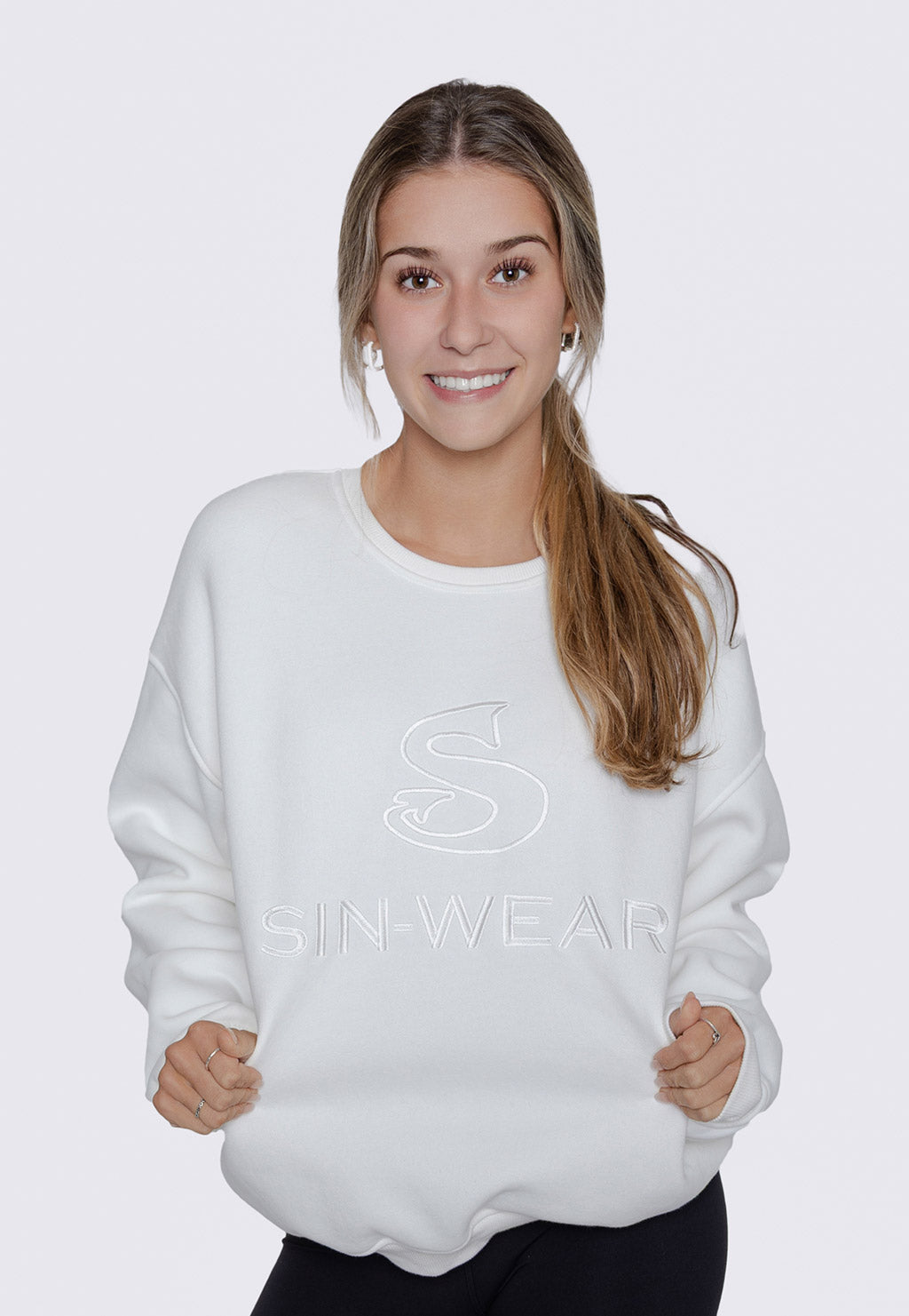 Person wearing a white sweatshirt with 'Sin-Wear' logo and text on a plain background