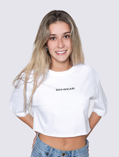 Person wearing a white crop top with 'SIN-WEAR' text on a plain background