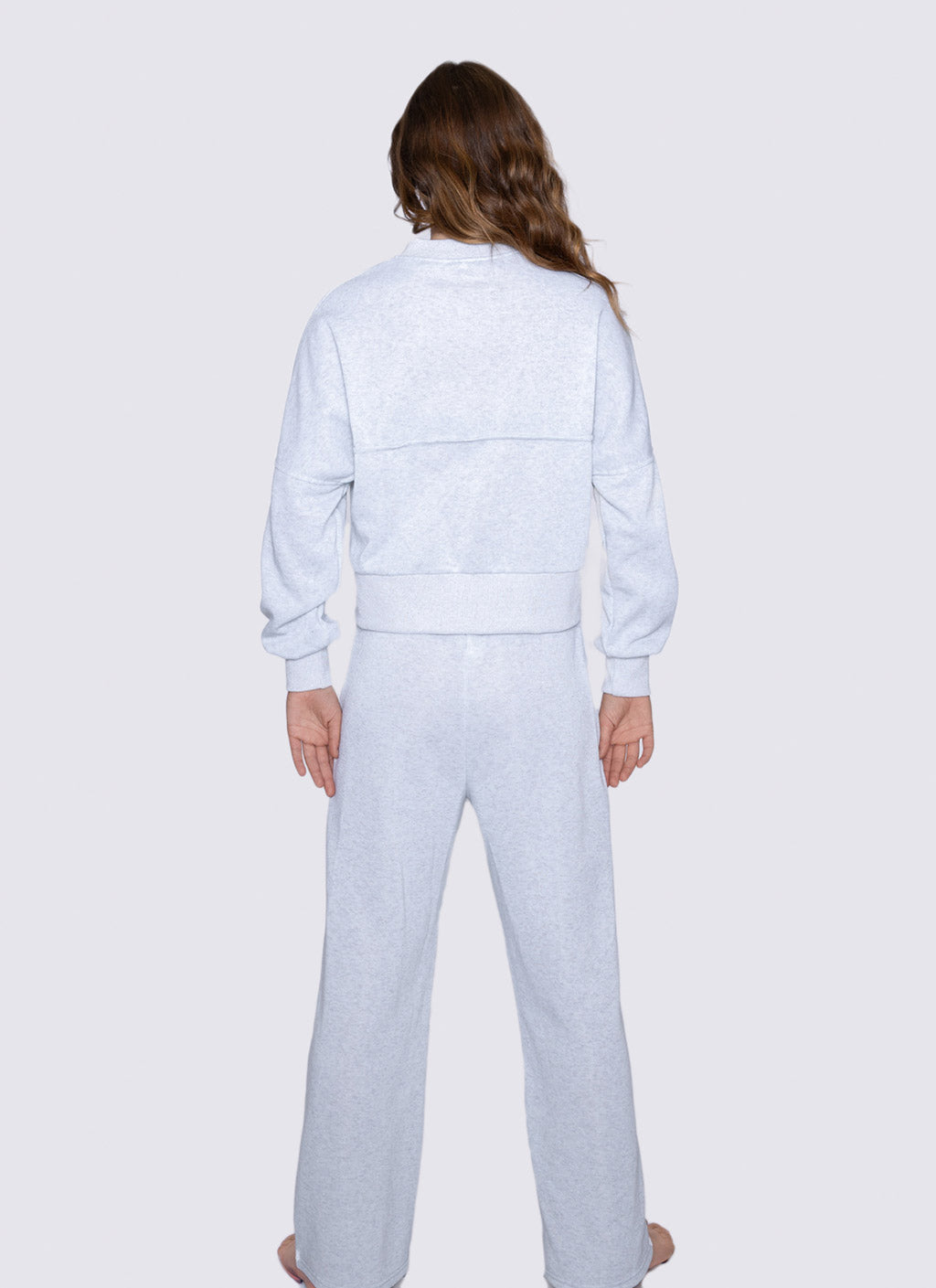 Person wearing a light gray tracksuit on a white background
