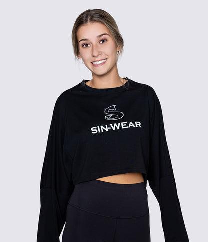 Woman wearing a black long sleeve crop top with 'SIN-WEAR' logo on a light gray background