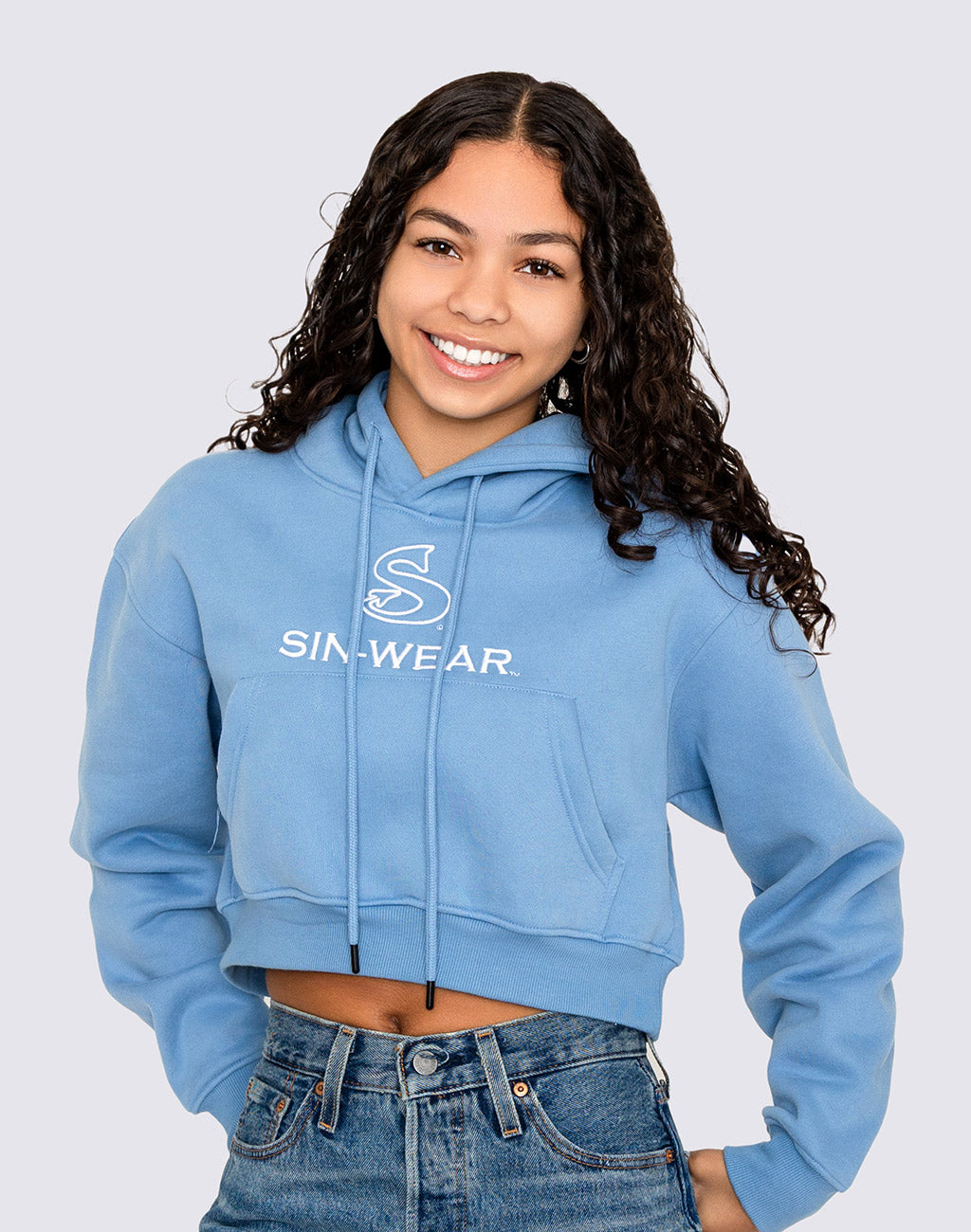 Person wearing a blue crop hoodie with 'Sin-Wear' logo on a light gray background