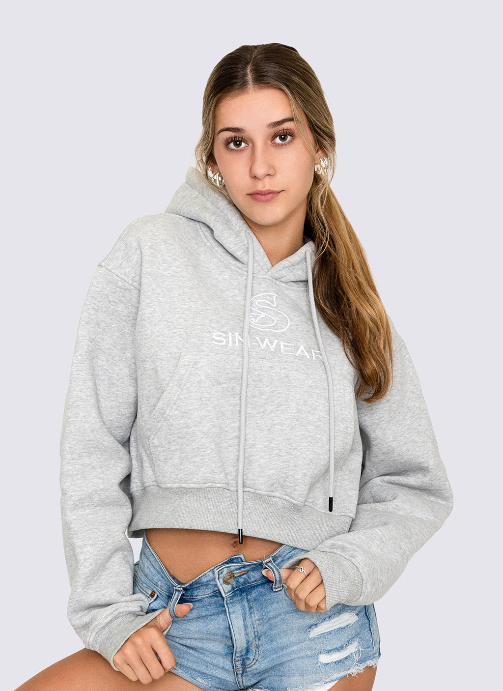 Woman wearing a gray crop hoodie with 'Sin-Wear' branding on a light gray background
