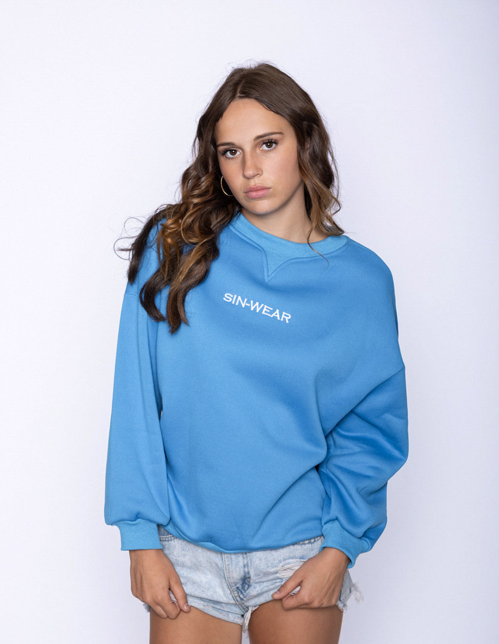 Woman wearing a blue sweatshirt with 'SIN-WEAR' logo on a white background