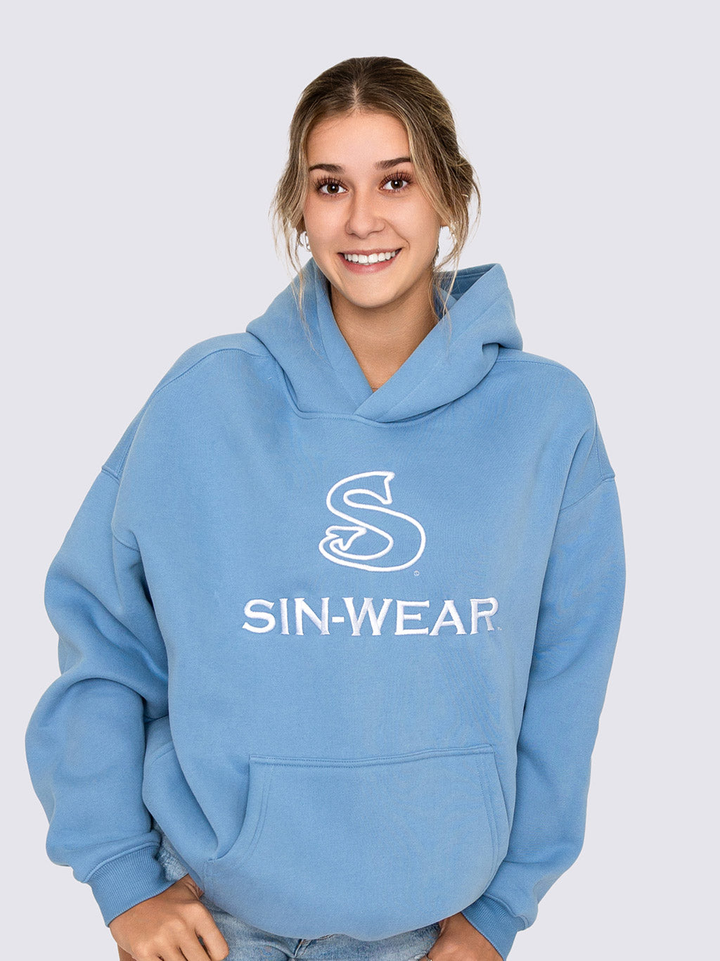 Person wearing a blue hoodie with 'SIN-WEAR' logo on a light gray background