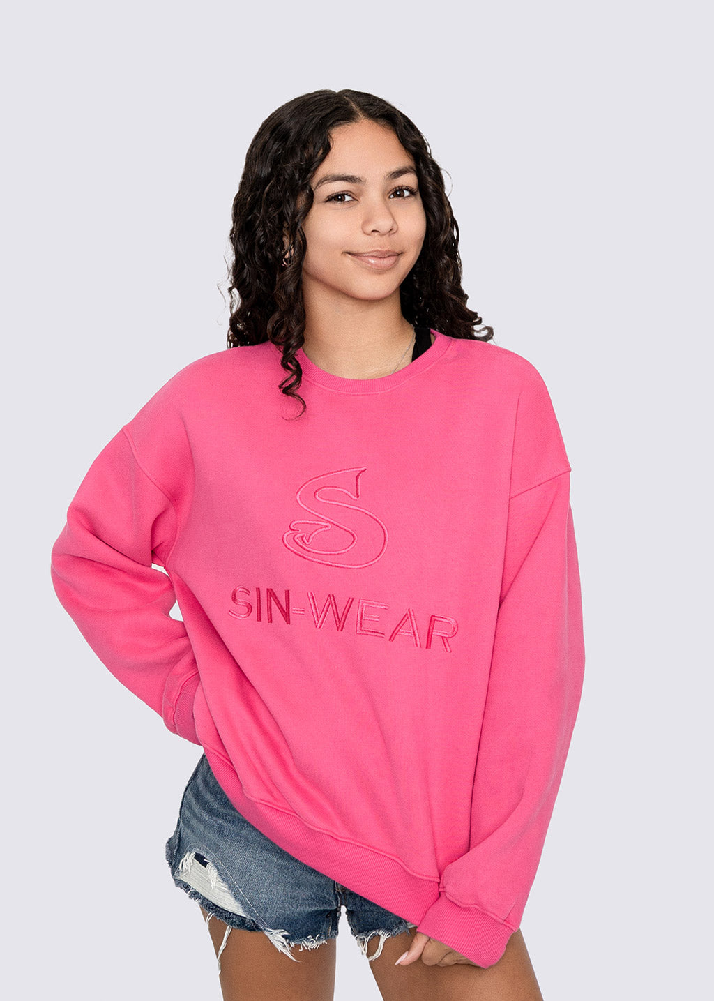 Person wearing a pink sweatshirt with 'Sin-Wear' branding on a plain background