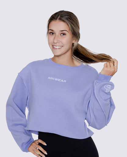 Woman wearing a light purple sweatshirt with 'SIN-WEAR' branding on a plain background