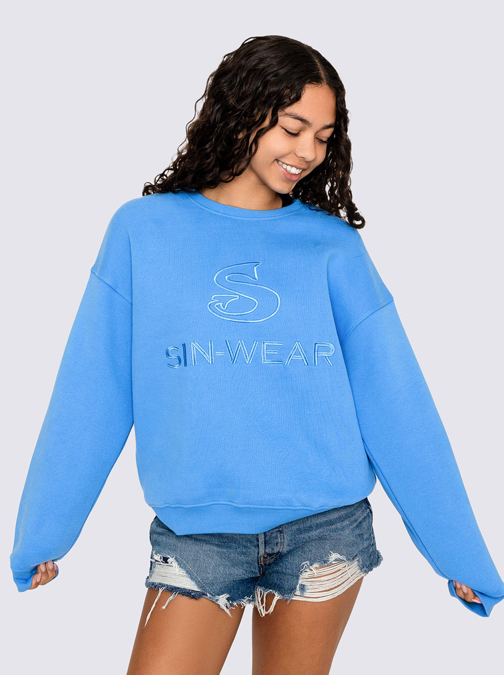 Person wearing a blue sweatshirt with 'SIN-WEAR' logo on a plain background